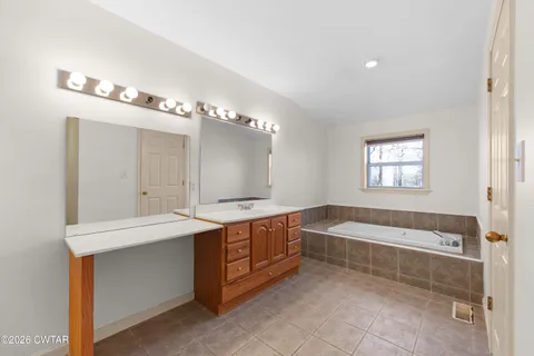 a spacious bathroom with a tub double sink and mirror