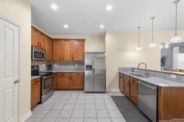 a kitchen with stainless steel appliances granite countertop a sink a stove a refrigerator and a microwave