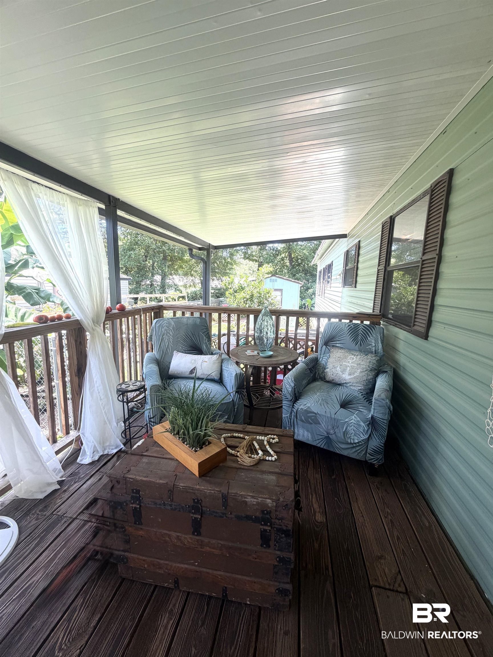 1620 Del Rey Drive Lillian, AL 36549 - Photo 5 of 45 Covered porch featuring wood-finish decking, light green exterior siding, and a slatted ceiling