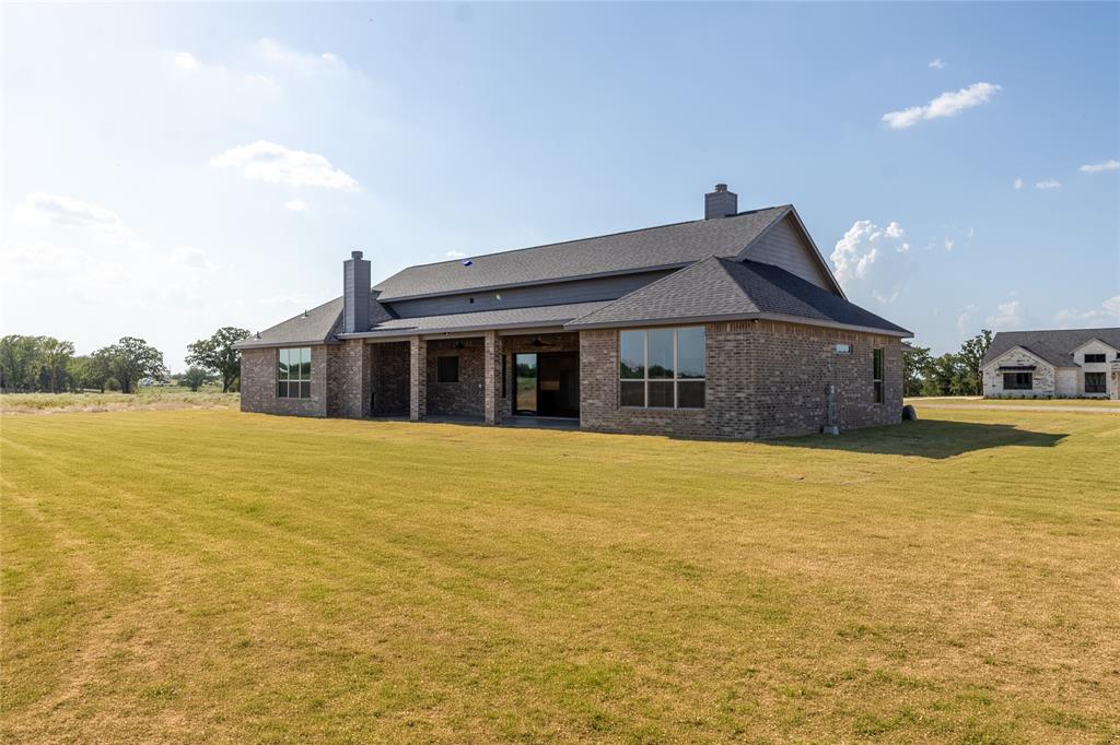 115 Red Bud Road Boyd, TX 76023 - Photo 37 of 38 Expansive lawn area encompassing a brick exterior with dark trim and multiple windows
