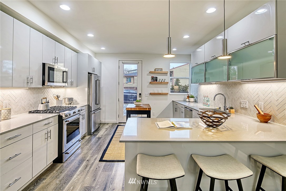 2858 Southwest Adams Street Seattle, WA 98126 - Photo 8 of 24 a kitchen with kitchen island a white counter top space a sink cabinets and stainless steel appliances