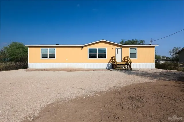a view of a house with backyard and chairs