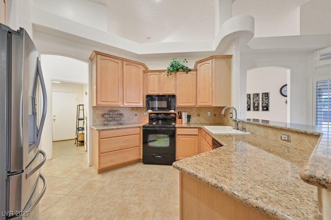 6120 Farm Road Las Vegas, NV 89131 - Photo 9 of 30 Kitchen with light brown cabinetry, black appliances, tasteful backsplash, and light tile patterned floors