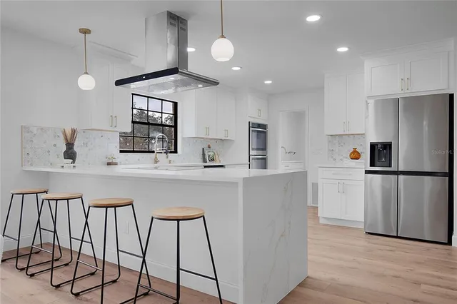 a large white kitchen with kitchen island a sink a stove and a refrigerator