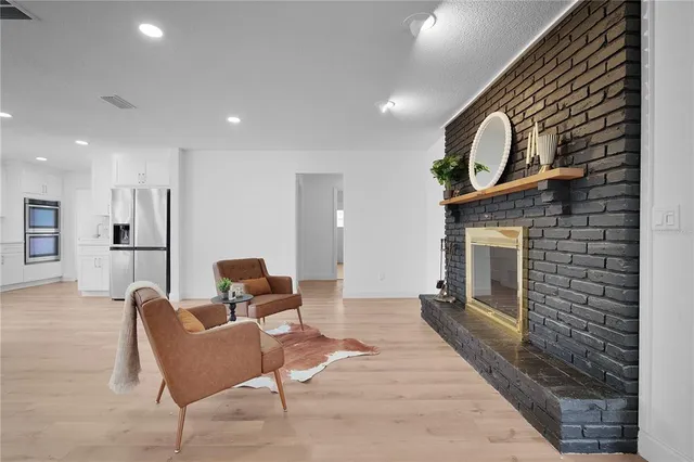 a living room with furniture a wooden floor and a kitchen view