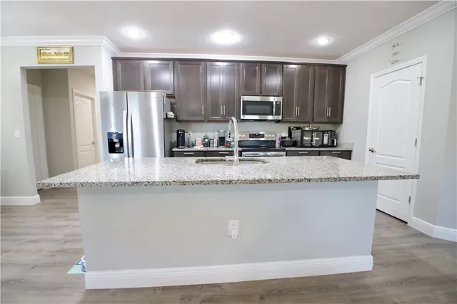 a kitchen with stainless steel appliances granite countertop a sink a stove a refrigerator a sink and a counter top space