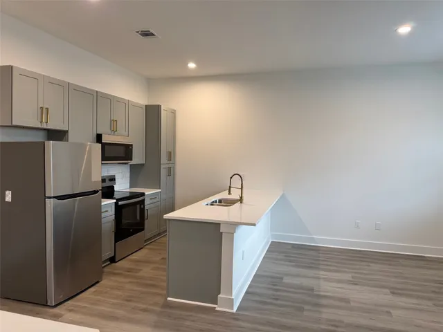 a kitchen with kitchen island a sink wooden floor and stainless steel appliances