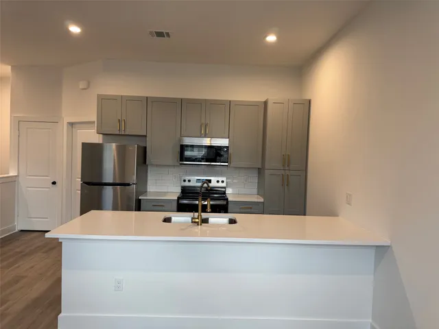 a kitchen with kitchen island a sink stainless steel appliances and cabinets