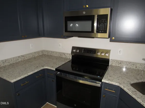 a kitchen with granite countertop a stove and a microwave