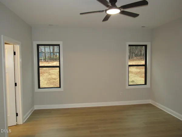 a view of an empty room with wooden floor and window