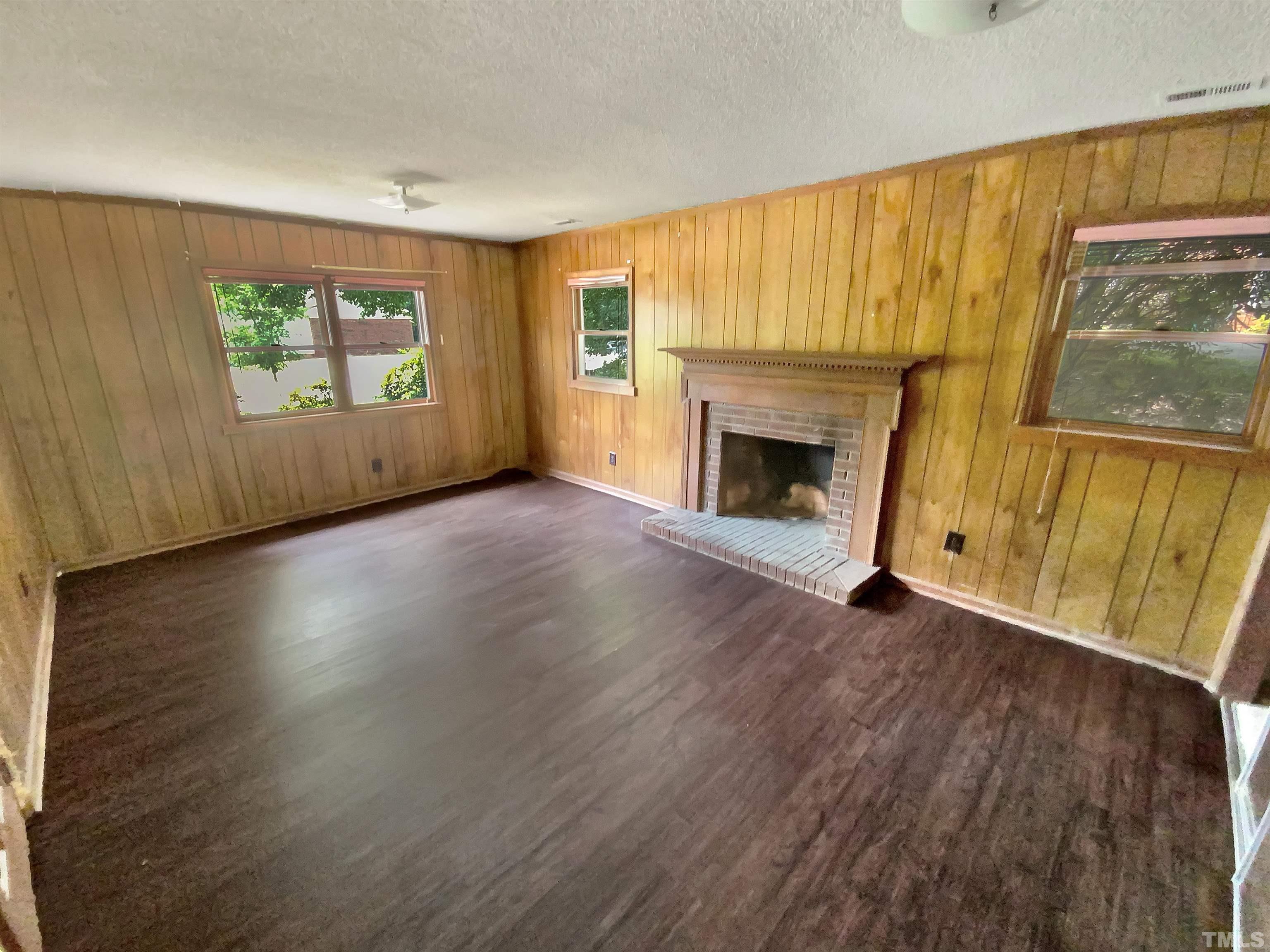 7508 Mine Shaft Road Raleigh, NC 27615 - Photo 5 of 18 an empty room with windows a fireplace and wooden floor