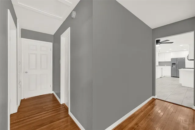 a view of a hallway with wooden floor and a bathroom