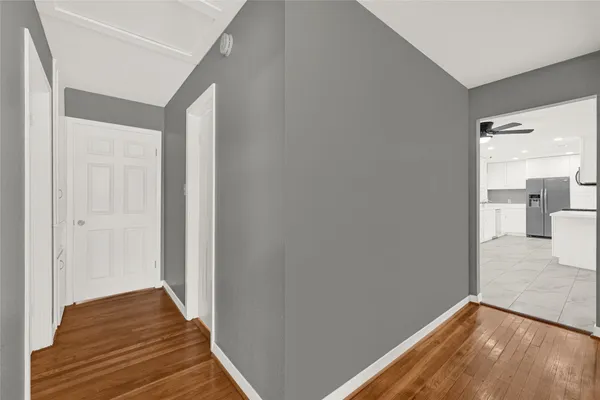 a view of a hallway with wooden floor and a bathroom