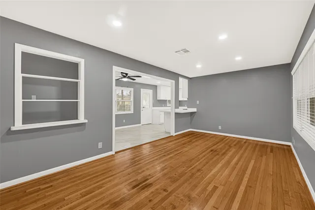 a view of empty room with wooden floor and fan