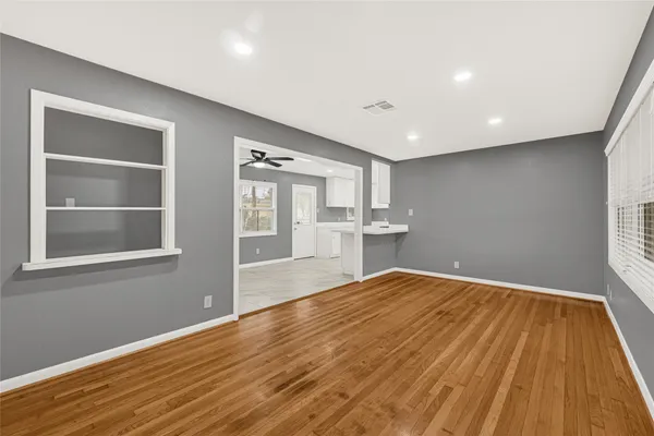 a view of empty room with wooden floor and fan
