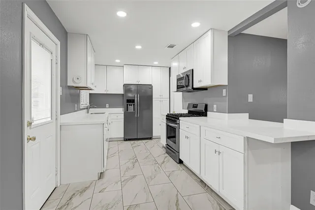 a kitchen with white cabinets and refrigerator