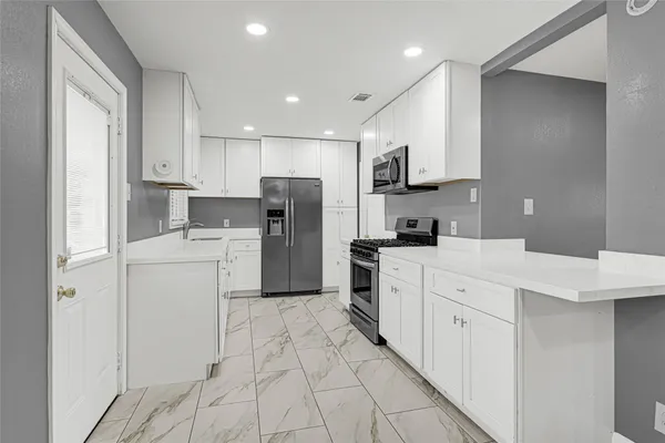 a kitchen with white cabinets and refrigerator