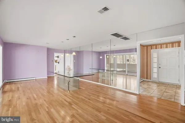 a view of empty room with wooden floor and fan