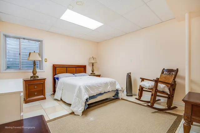 a bedroom with a bed a chair and potted plant on the dresser