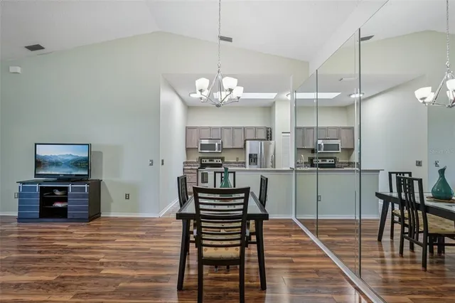 a kitchen with stainless steel appliances kitchen island granite countertop a refrigerator a stove and a dining table with wooden floor