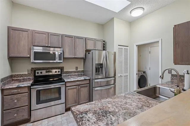 a kitchen with granite countertop a stove sink and refrigerator