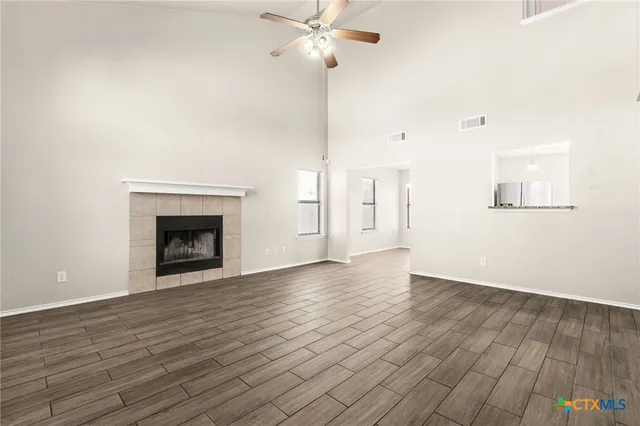 a view of an empty room with wooden floor and a fireplace