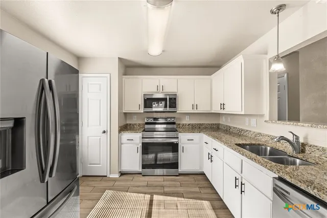 a kitchen with stainless steel appliances granite countertop a refrigerator and a stove top oven