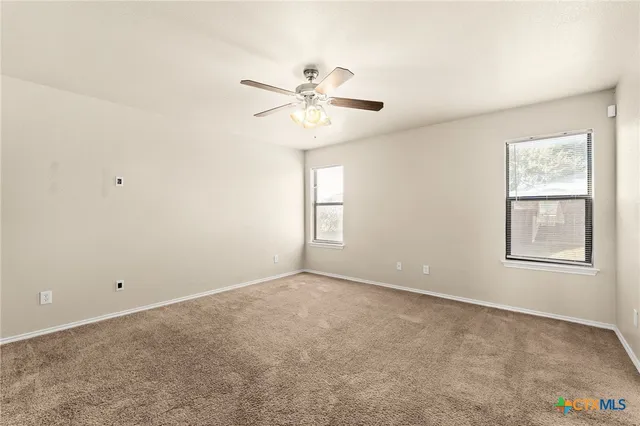 an empty room with windows and fan