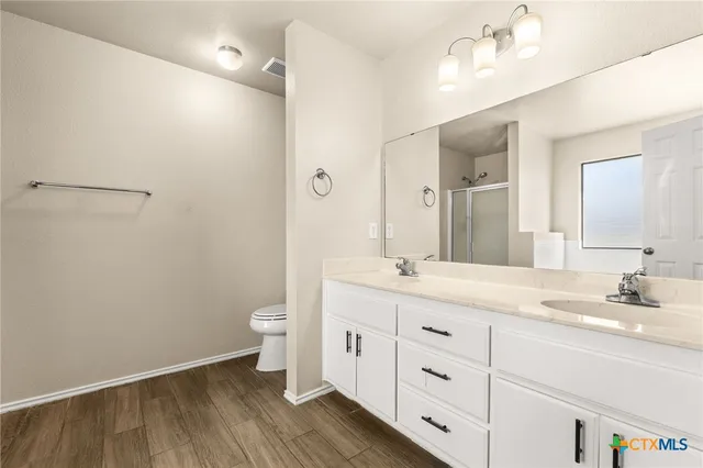 a spacious bathroom with a double vanity sink a toilet and a mirror
