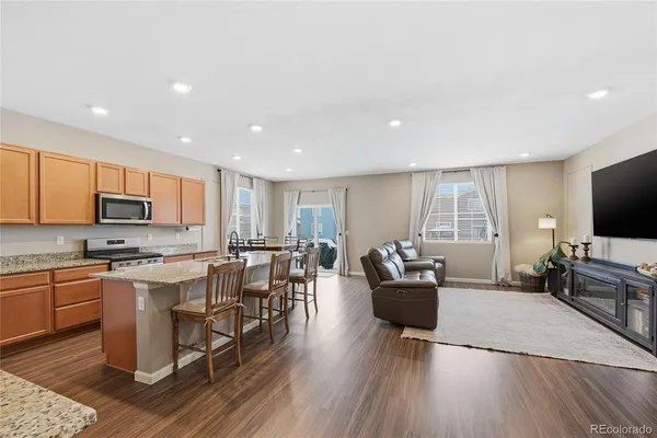 a living room with stainless steel appliances furniture and a flat screen tv