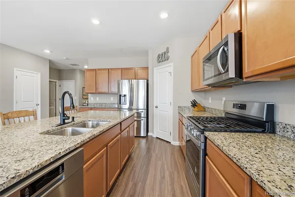 a kitchen with stainless steel appliances granite countertop a stove a sink and a refrigerator