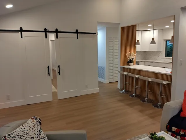 a living room with furniture a large window and stainless steel appliances