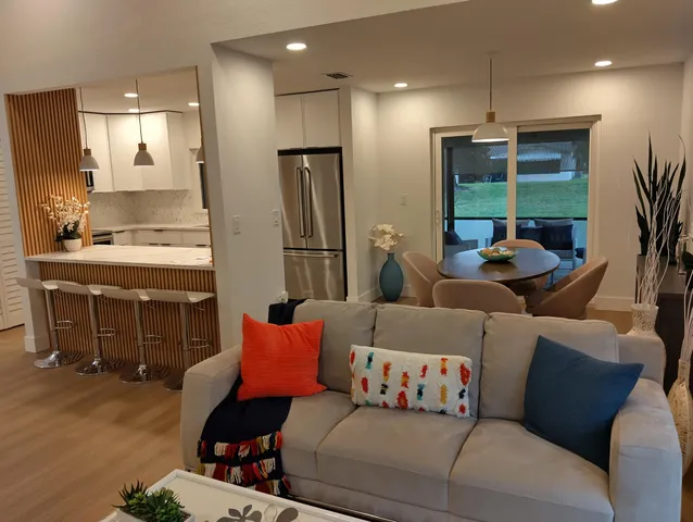 a living room with furniture and potted plants with wooden floor