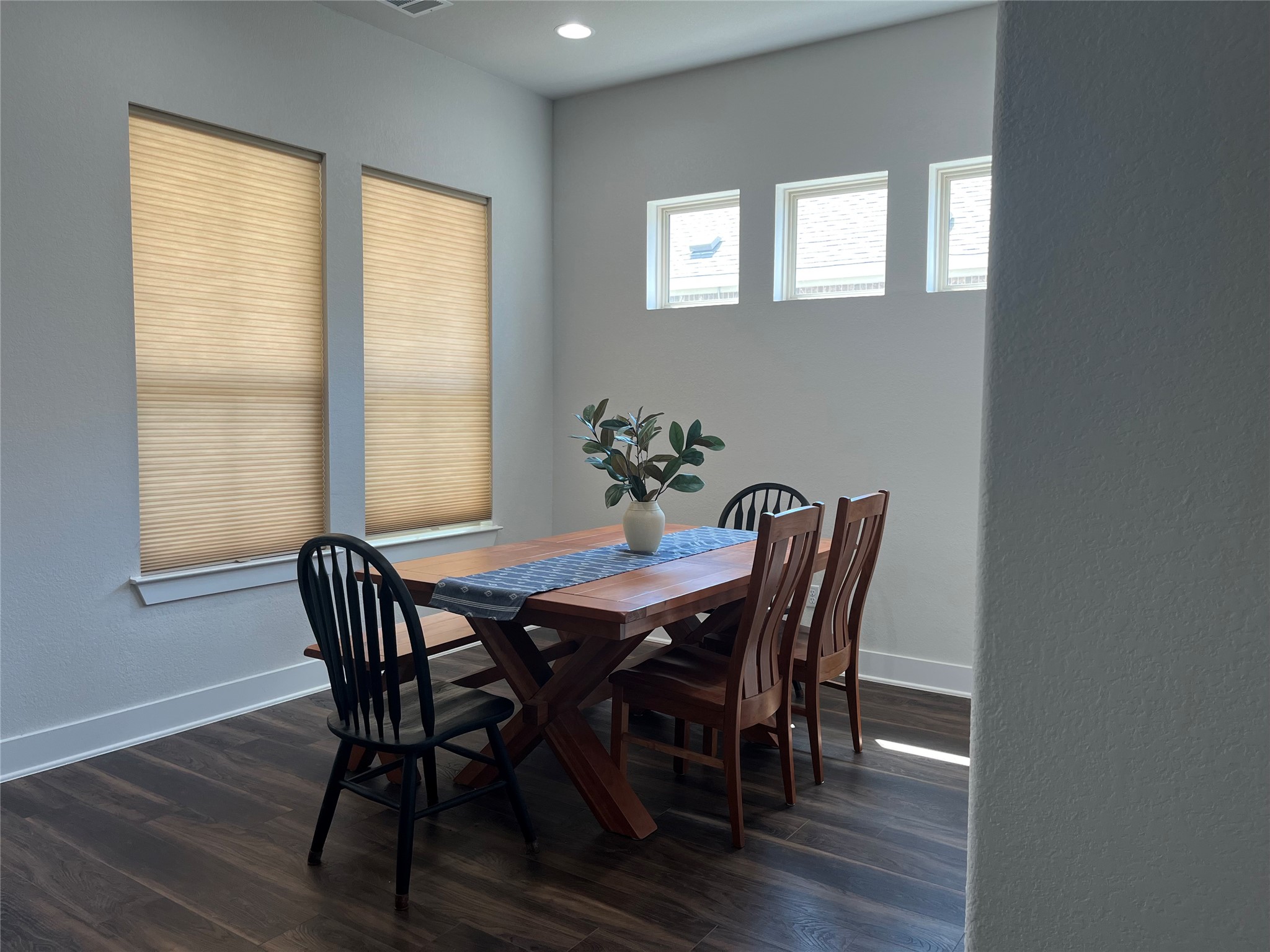 4420 Kings Cross Road Pflugerville, TX 78660 - Photo 2 of 13 Natural light filters through the dining room's multiple windows, highlighting rich wood flooring.