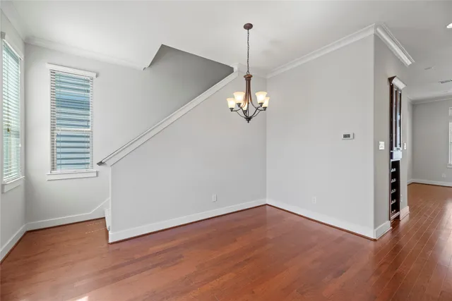 a view of a room with wooden floor chandelier and windows