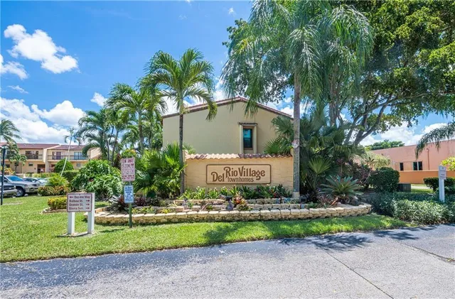 a sign board with a house and garden in the background