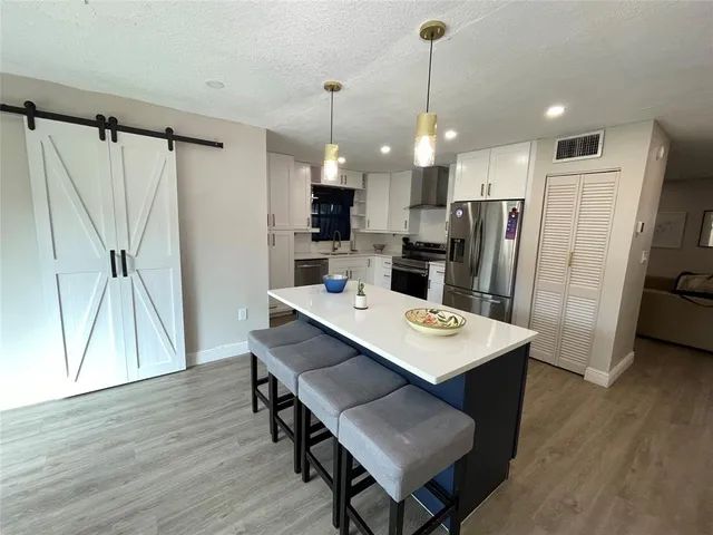 a kitchen with stainless steel appliances a refrigerator a sink a stove a dining table and chairs