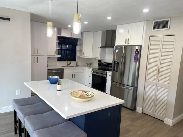 a kitchen with stainless steel appliances granite countertop a sink a refrigerator a stove a microwave and island