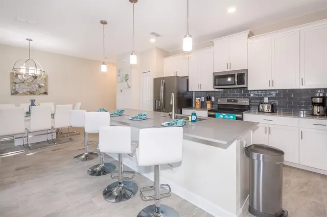 a kitchen with stainless steel appliances kitchen island granite countertop a sink a stove a refrigerator and cabinets