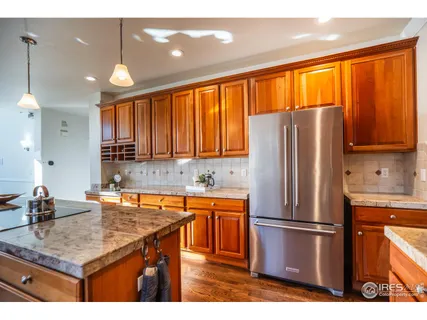 a kitchen with stainless steel appliances granite countertop a refrigerator a sink a stove with wooden cabinets