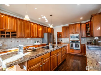 a kitchen with stainless steel appliances granite countertop a stove top oven a sink dishwasher a dining table and chairs with wooden floor