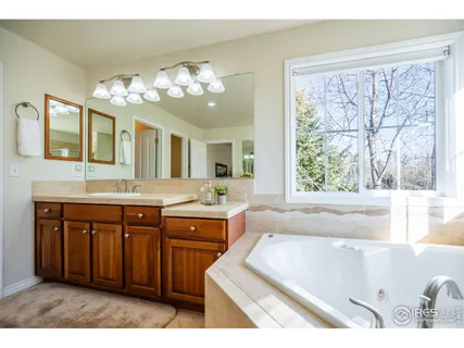 a spacious bathroom with a tub double sink and a large mirror