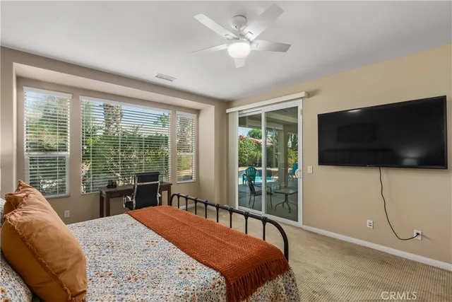 a bedroom with a bed a flat screen tv and a large window with the view of balcony