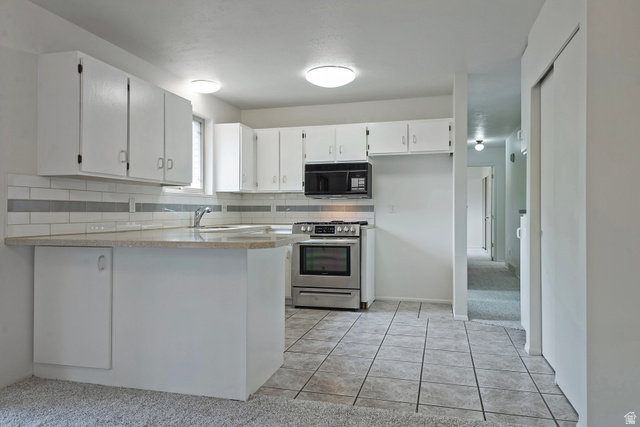 1722 Kimsbrough Road Sandy, UT 84092 - Photo 9 of 29 Kitchen featuring white cabinetry, light-toned countertops, a subway tile backsplash with accent stripe, stainless steel range with overhead microwave, and tile flooring