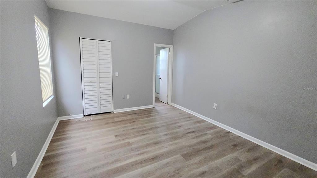 3410 15th Street Southwest Lehigh Acres, FL 33976 - Photo 13 of 31 an empty room with wooden floor and windows