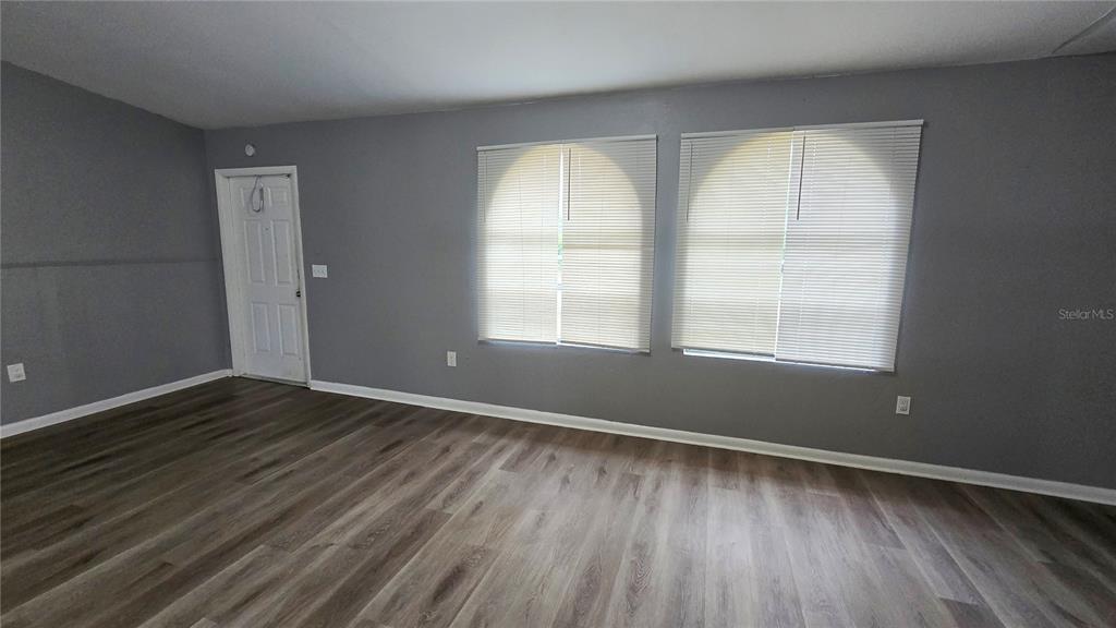 3410 15th Street Southwest Lehigh Acres, FL 33976 - Photo 4 of 31 an empty room with wooden floor and windows