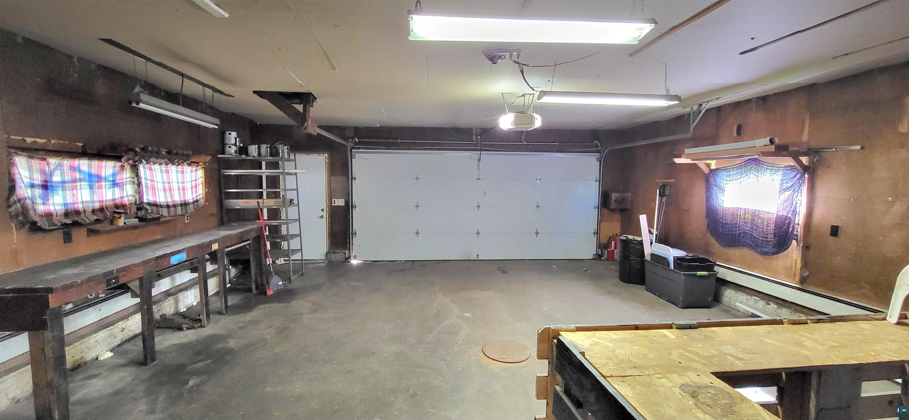 56 East 2nd Street Superior, WI 54880 - Photo 18 of 18 Spacious garage interior featuring a large white overhead door, concrete flooring, and ample lighting
