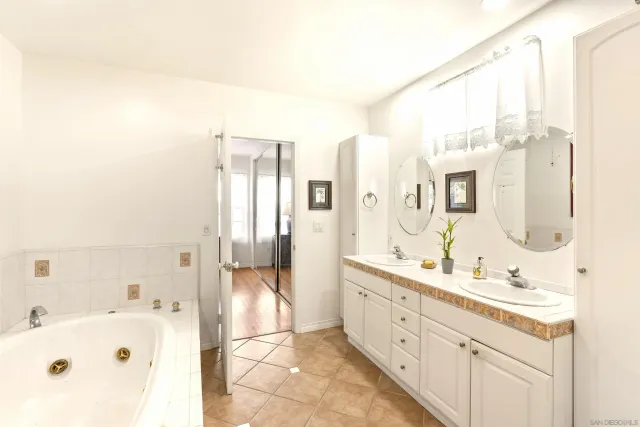 a spacious bathroom with a tub sink and mirror