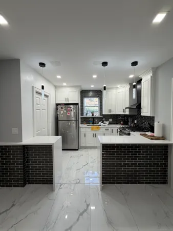 a large kitchen with stainless steel appliances a large counter top a stove and a refrigerator