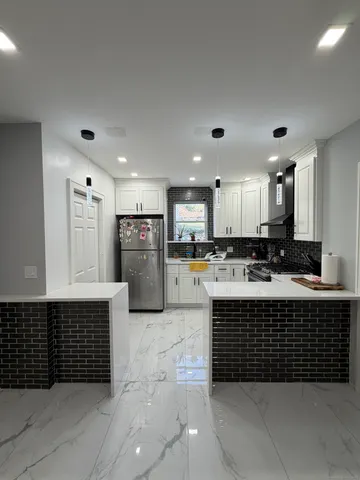 a large kitchen with stainless steel appliances a large counter top a stove and a refrigerator